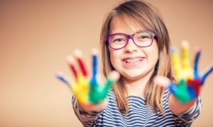 kid smiling with paint on hands