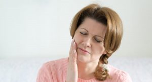 woman holding jaw in pain