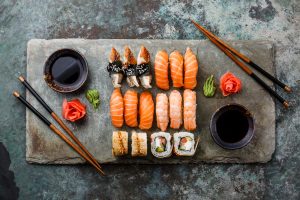 Sushi platter with a variety of rolls and fresh fish with chopsticks and soy dishes