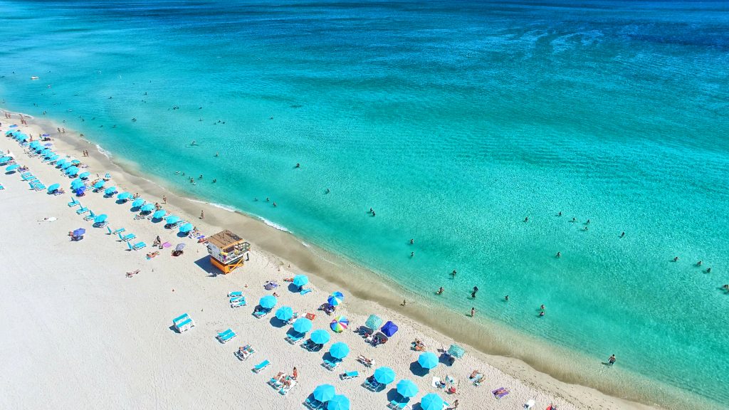 Aerial view of South Beach in Miami, FL with cabanas and pale green and blue ocean