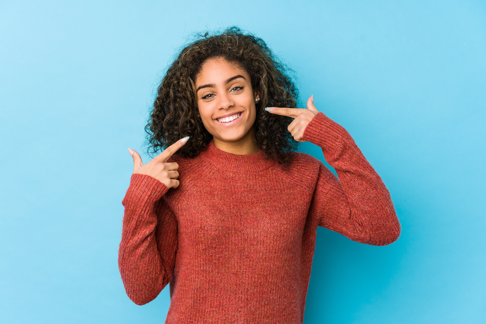 girl smiling and pointing to her teeth